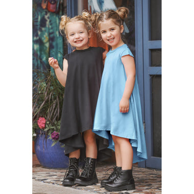 Two young girls in dresses standing outdoors with a colorful background.