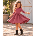Girl wearing the Nova organic cotton twirl dress in muted berry, featuring a full circle skirt, round neckline, and delicate ruched sleeves.