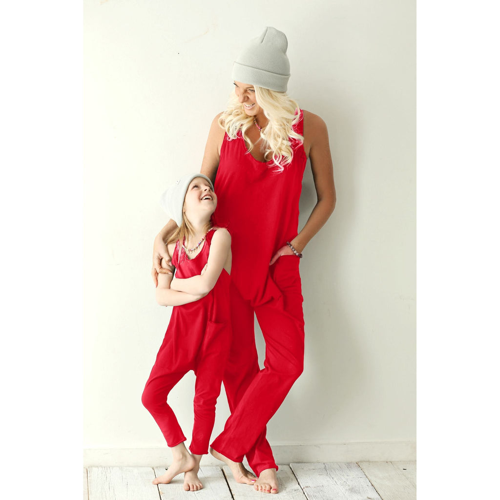 Woman and child in matching red outfits standing on a light wooden floor with a white background