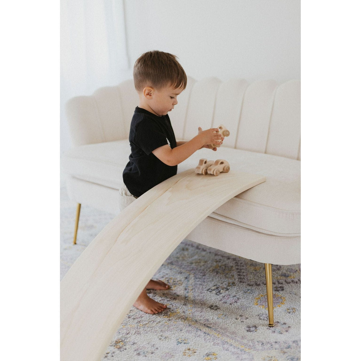 Child balancing on a ShopMyLittleSongbird balance board toy, rocking and playing on a colorful wooden rocker.