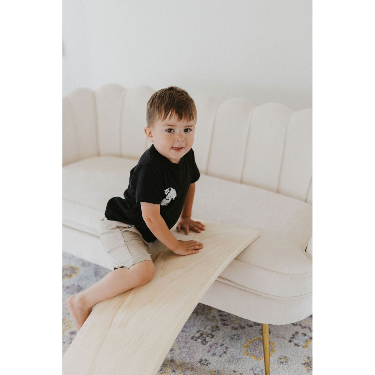 Child playing on a ShopMyLittleSongbird balance board rocker toy, featuring a colorful, curved wooden design for balance and fun.
