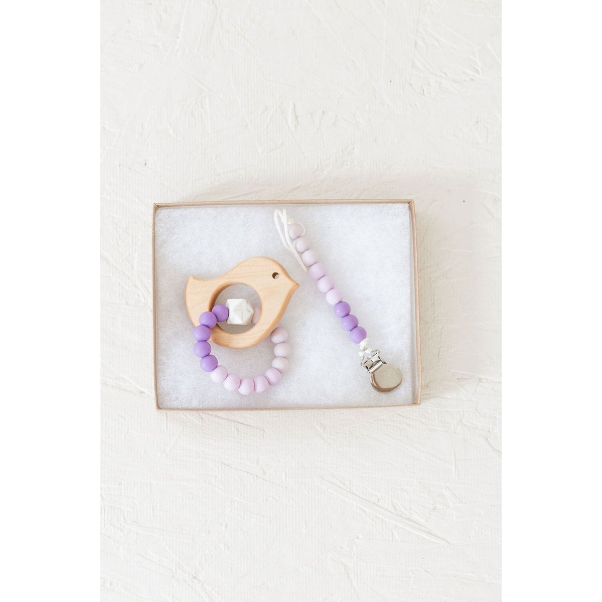 Wooden teether with silicone ring for babies, natural wood and soft silicone detail, designed for soothing teething discomfort.