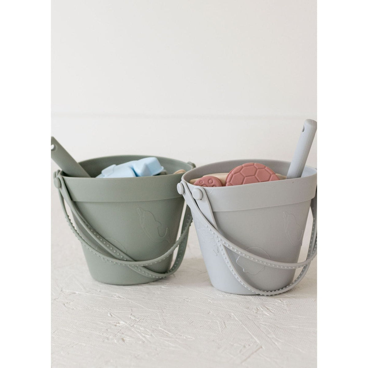 Colorful silicone sand toy bucket with toys and shovel for kids, perfect for beach or sandbox play.