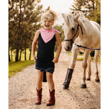 Child standing next to a white horse on a dirt road with trees in the background