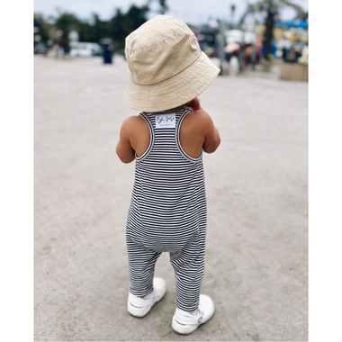 Child wearing a striped romper and sun hat on a beach