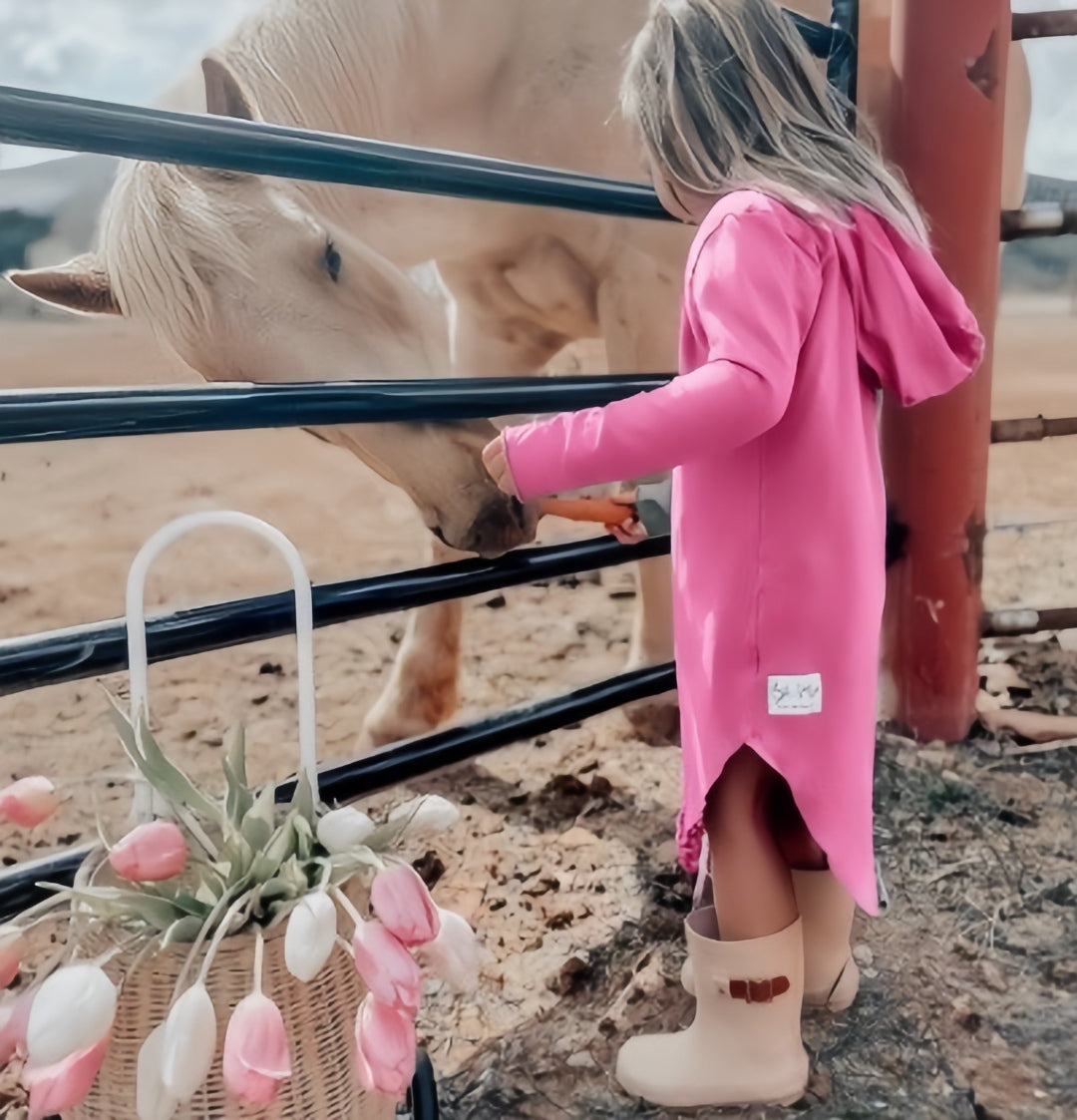 Be Mi Los Angeles child feeding a horse in a pink hooded dress
