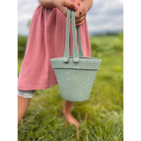 Silicone sand toy bucket with colorful toys and shovel for kids, designed for outdoor play and sandcastle building.