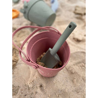 Silicone sand toy bucket with colorful toys and a shovel, perfect for kids' outdoor play and beach fun.