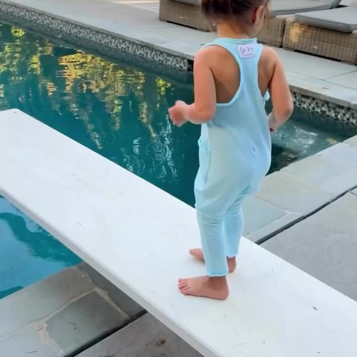 little girl walking by the pool in blue romper