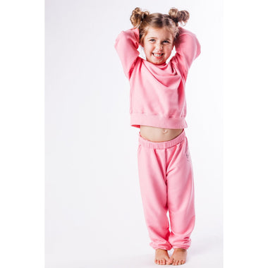 Child wearing a pink organic sweatshirt and pants  on a white background