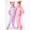 Two children wearing matching organic pink and lavender pajamas on a white background