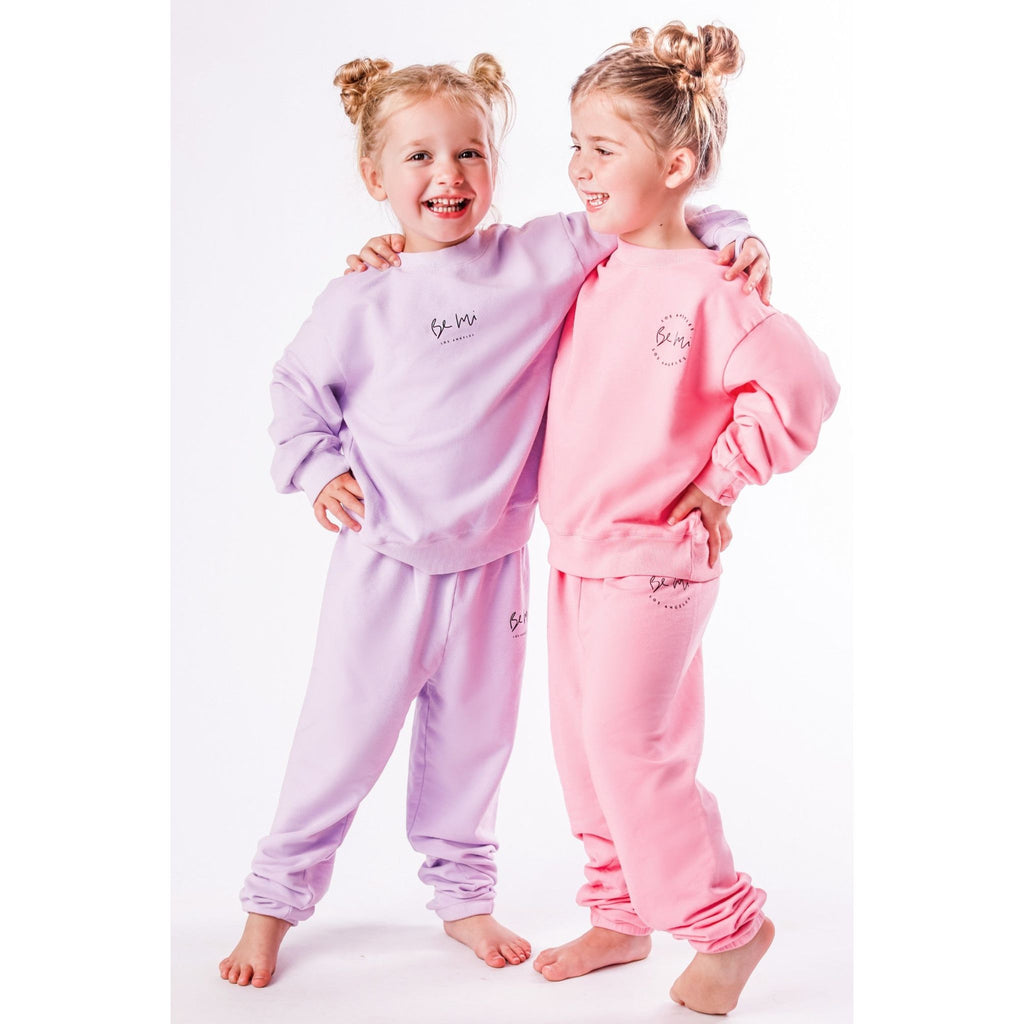 Two children wearing matching organic pink and lavender pajamas on a white background