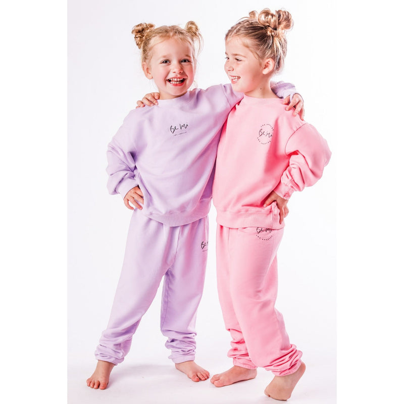 Two children wearing matching organic pink and lavender pajamas on a white background