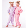 Two children wearing matching pink and lavender pajamas on a white background