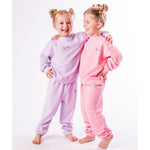 Two children wearing matching pink and lavender pajamas on a white background