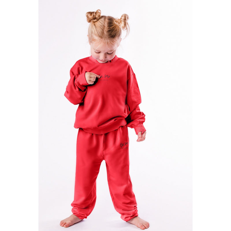 Child wearing a red outfit with a logo on a white background