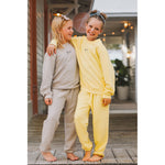Two children in matching outfits standing on a wooden deck.