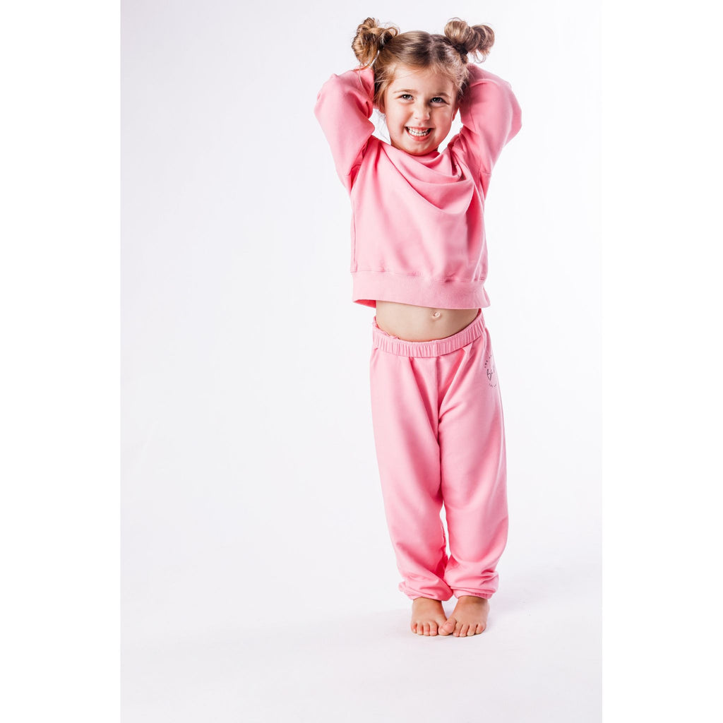 Child wearing a lavender sweatshirt and pants set on a white background