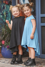 Two young girls in dresses standing outdoors with a colorful background.