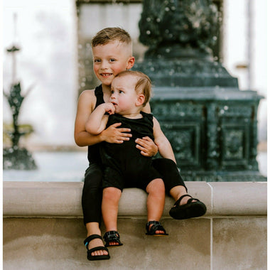 Black baby romper by Be Mi Los Angeles, soft cotton fabric, featuring short sleeves and snap closures for easy dressing.